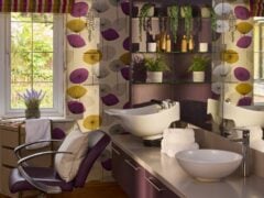 Colourful salon interior with floral wallpaper, chair, and basin.