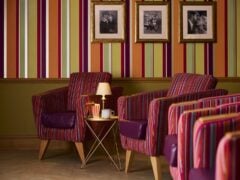 Striped lounge chairs with framed photos on wall.