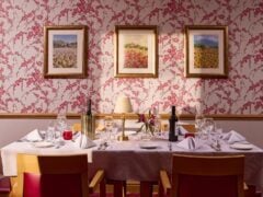 Elegant dining table in a floral wallpapered room.
