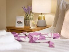 Cosy bedside with lamp, flowers, and photo frame.