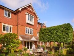 Red-brick house with garden and outdoor seating area.