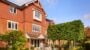 Red-brick house with garden and outdoor seating area.