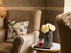Cosy armchair beside table with flowers and drink