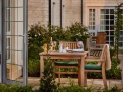 Outdoor table set for two with wine and food.