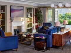 Modern living room with blue chairs and fireplace.