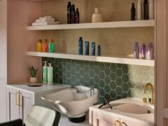Modern hair salon with washbasin and products on shelves.