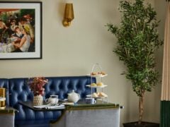 Elegant tea setting with tiered tray and painting.
