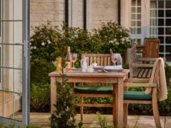 Outdoor dining table with wine and plates.