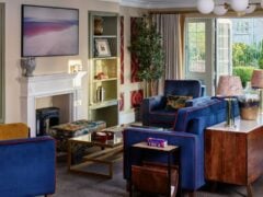 Modern lounge with blue chairs and fireplace in a luxury dementia care home.