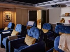 Cosy home cinema with blue armchairs and snacks.